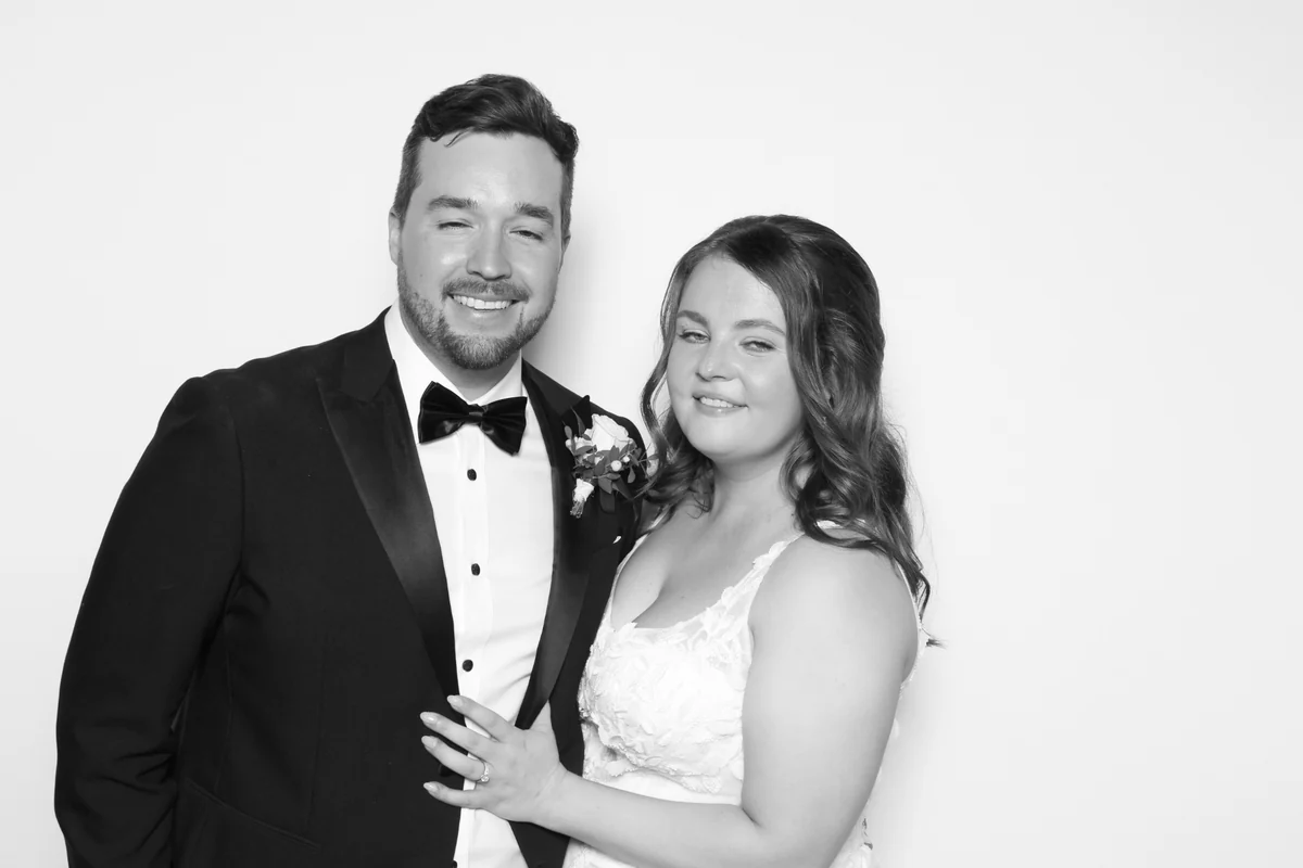 Rachel and Scott smiling together in their black-and-white photo booth portrait
