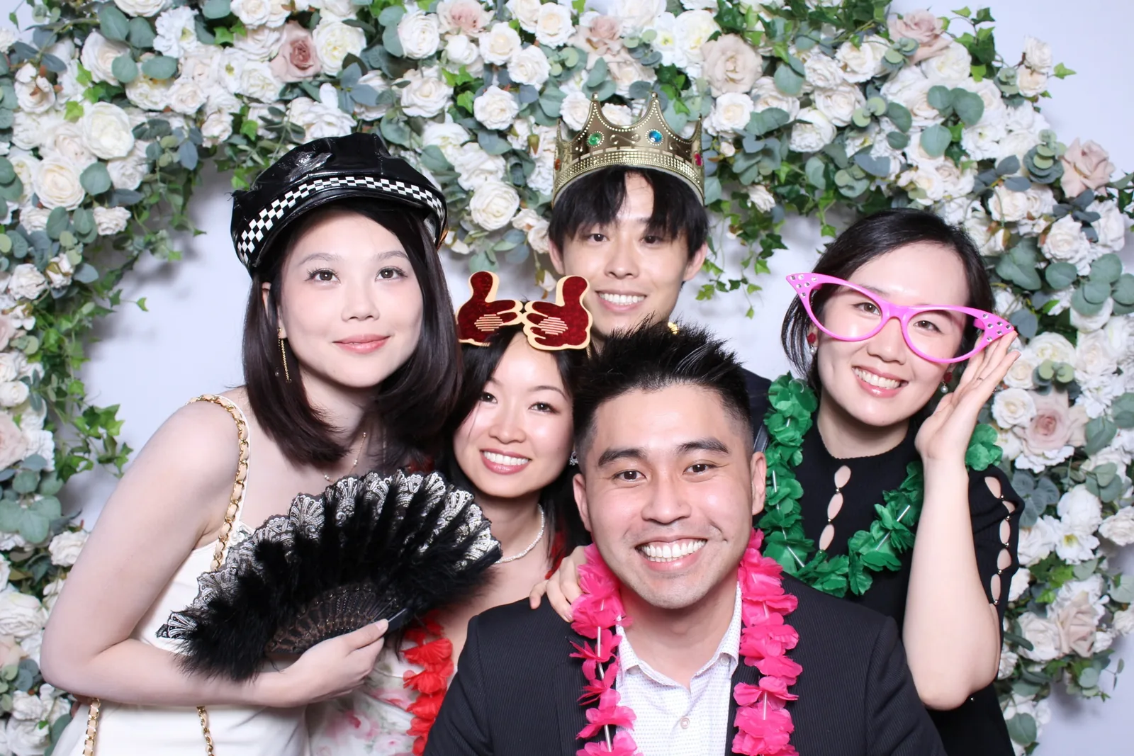 Guests enjoying a photo booth with a floral greenery backdrop, photo 2