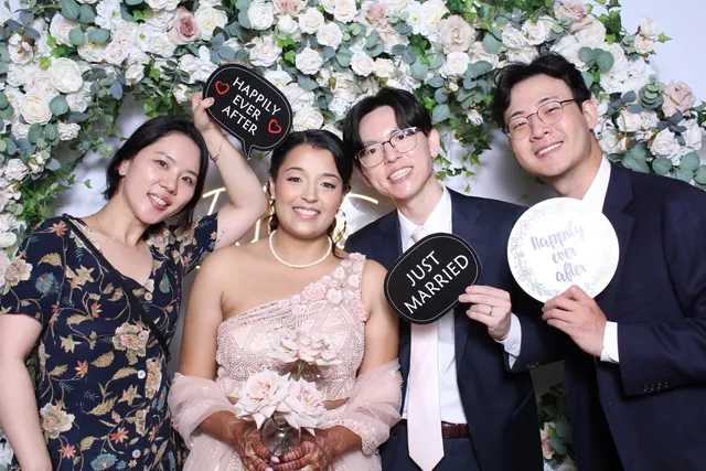 Guests enjoying a photo booth with a floral greenery backdrop, photo 3