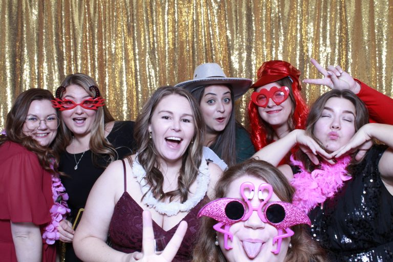 Guests posing in front of a gold sequin photo booth backdrop