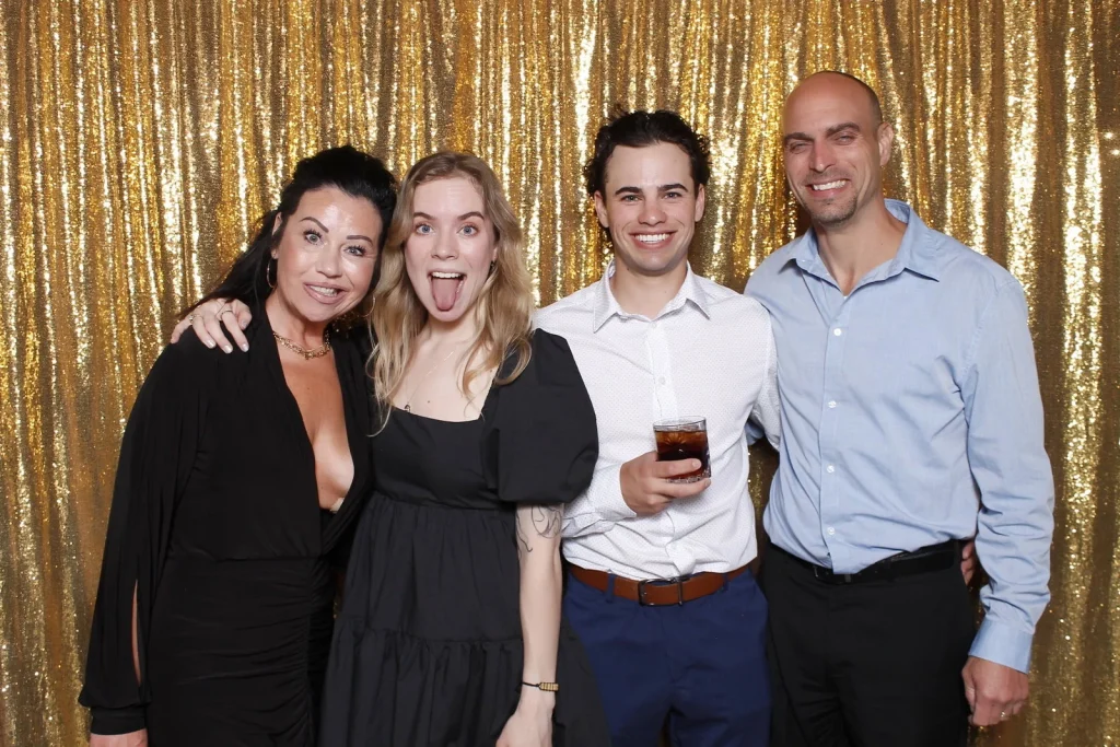 Four wedding guests posing together in front of a gold sequin backdrop