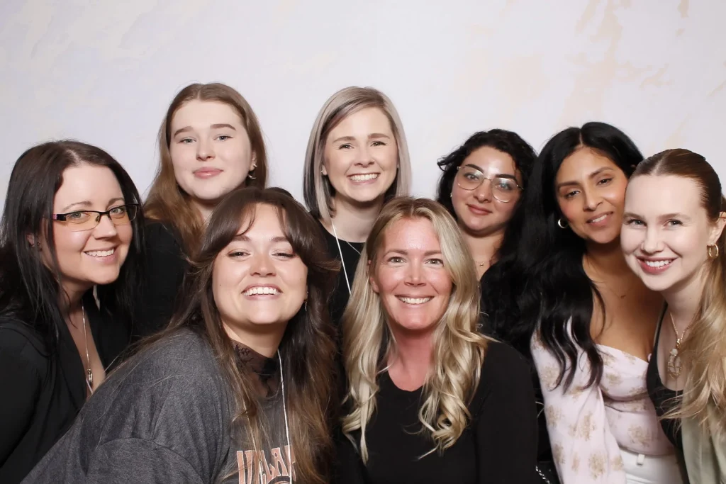 Eight EPN Social guests smiling together against a light white photo booth background