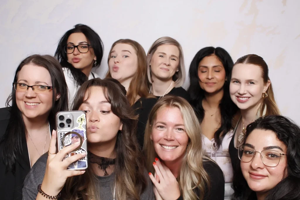 A group of EPN Social guests crowding into the photo booth frame with one guest holding a phone