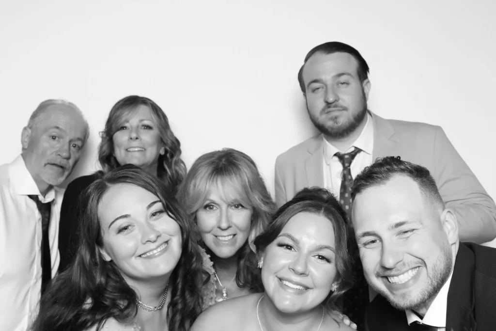 Seven wedding guests leaning together for a black-and-white group portrait