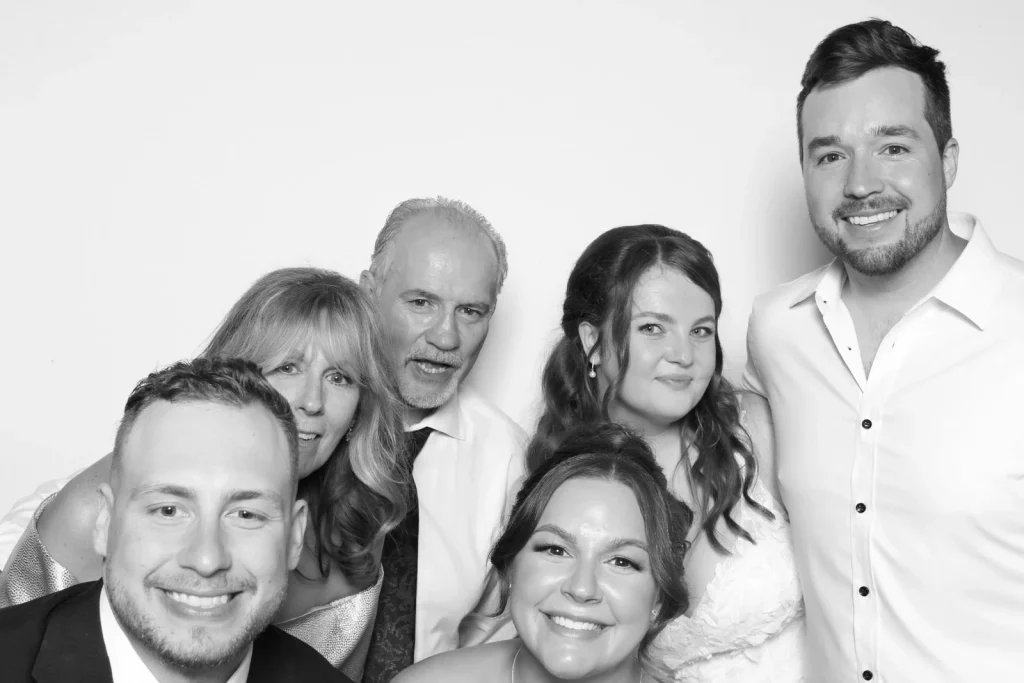 Six wedding guests gathering close for a black-and-white group portrait